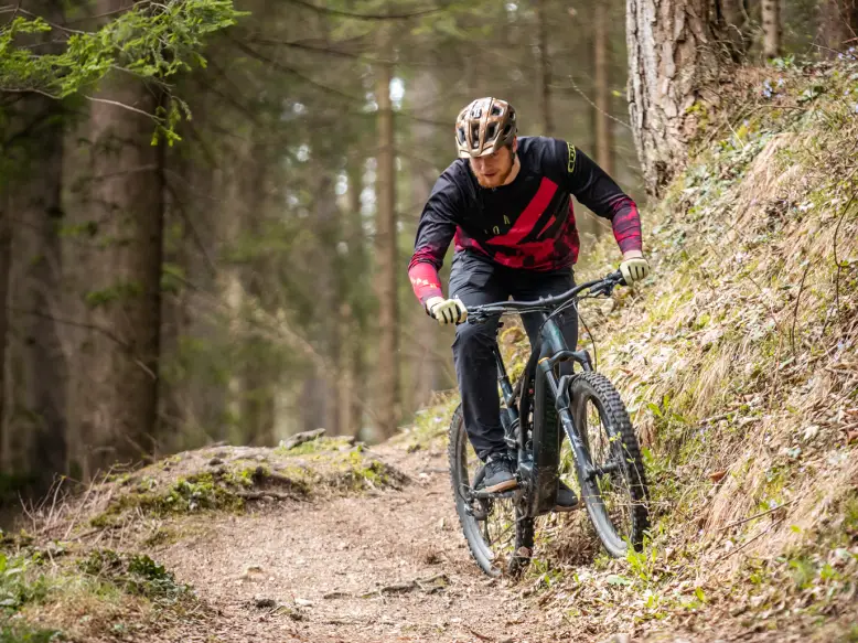 Kolesar na električnem kolesu v zavoju na gozdni poti