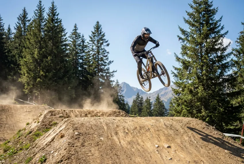 Kolesar na downhill kolesu izvaja velik skok v bike parku.