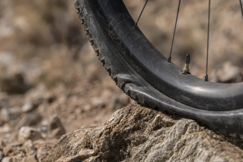 Bližnji posnetek široke tubeless pnevmatike, ki se prilagaja kamniti podlagi.