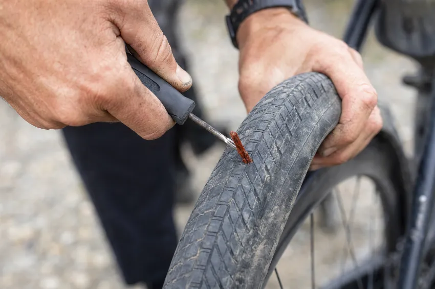 Od blizu prikazano vstavljanje čepa v predrto tubeless gravel pnevmatiko.