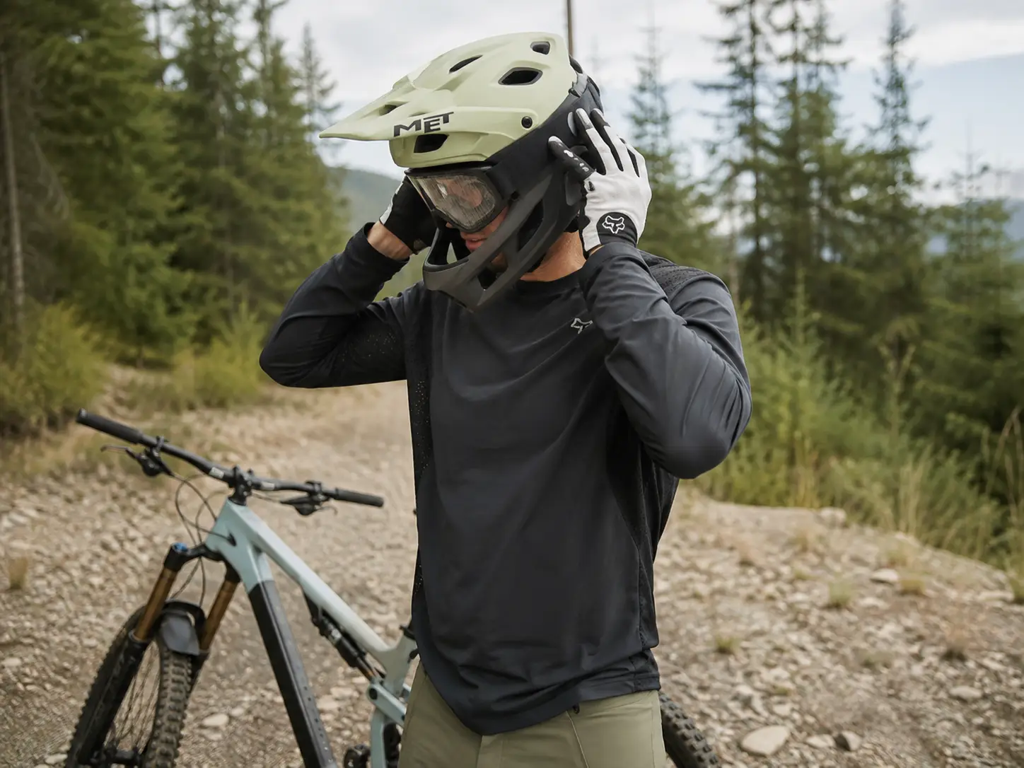 Kolesar si pred vožnjo pravilno namešča MTB kolesarsko čelado ob gorskem kolesu